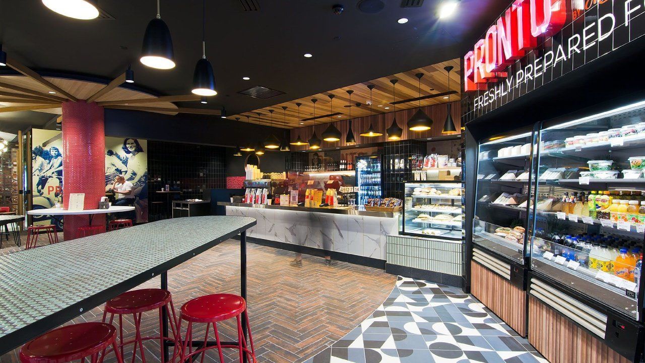 Interior of a cafe with a food display, seating, and signage.