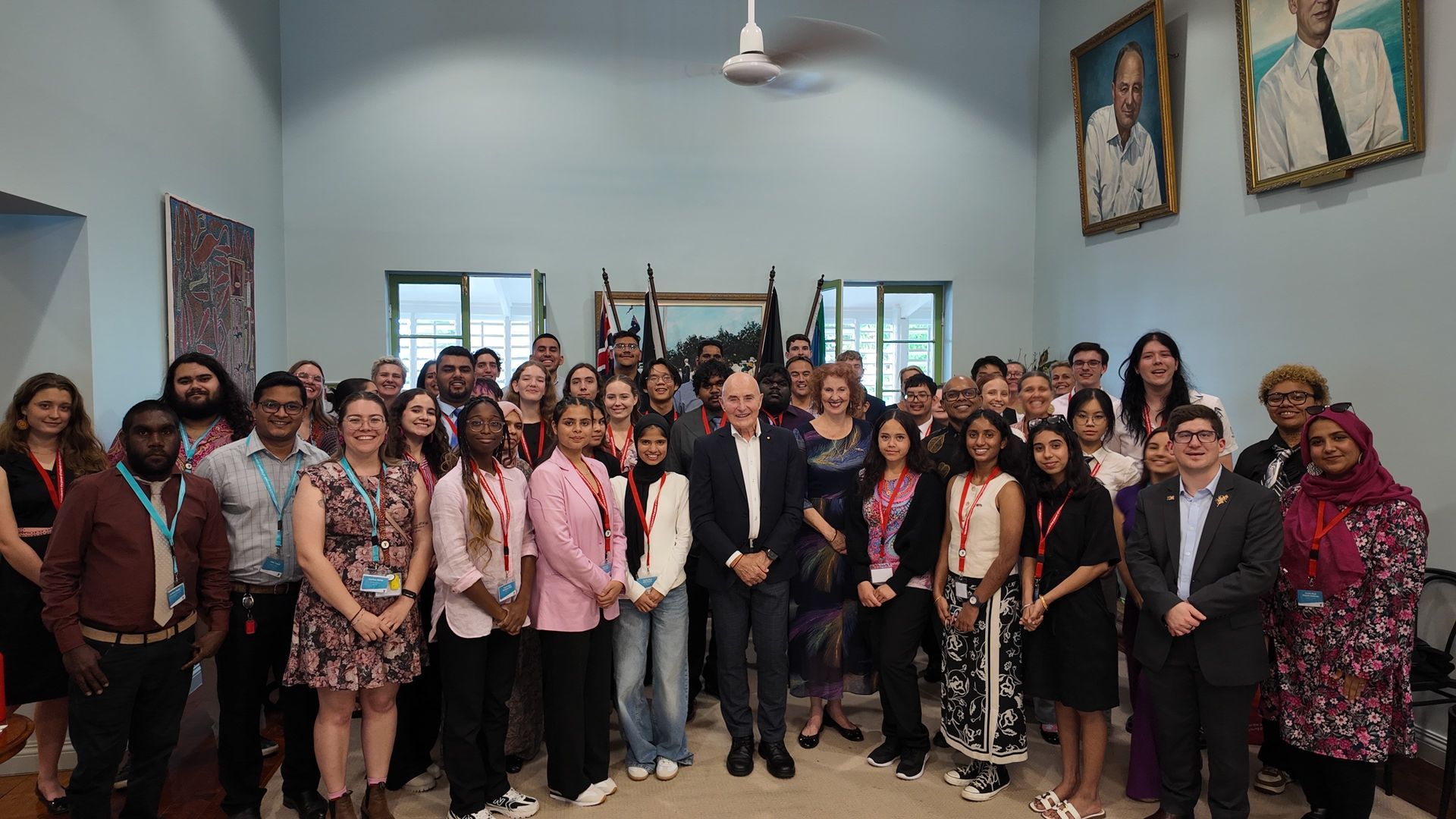 Group of people posing for a photo in a room with portraits.