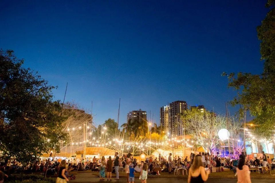A crowd of people are gathered in a park at night.