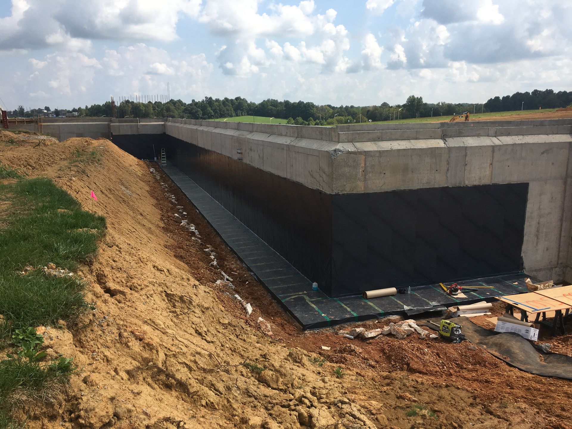 Person applying blue waterproof sealant to a concrete corner with a trowel.