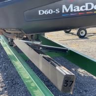 A close-up of a MacDon D60-S header showing a metal support beam labeled with the number 37 on a gravel lot.