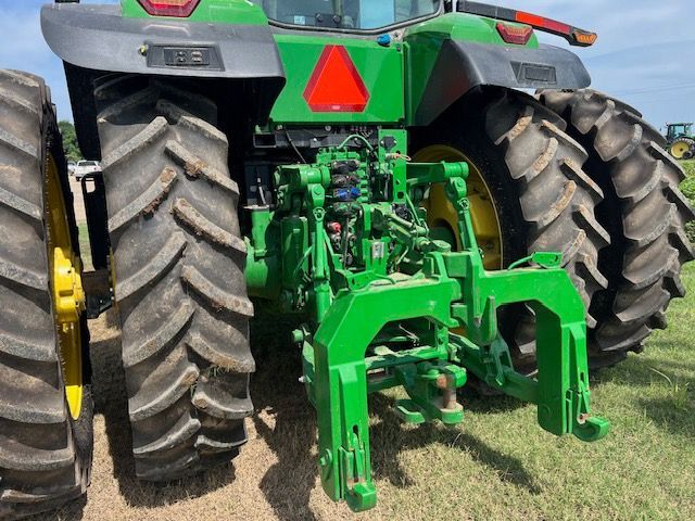 The rear view of a large green John Deere tractor with dual wheels parked on grass.