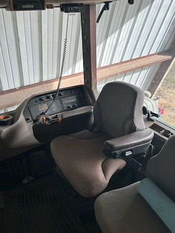 Interior view of a tractor cab featuring a brown upholstered driver's seat, steering column, and control dashboard.