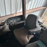 The interior cabin of a tractor, showing the driver's seat, steering console, and dashboard controls.