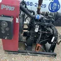 A red, industrial P110 engine unit with a black motor, gauges, and hoses, parked on gravel outdoors.