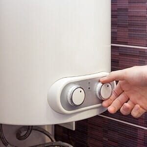 Man hands setting the temperature of water in Electric Boiler — Boiler Maintenance in Twin Falls, ID