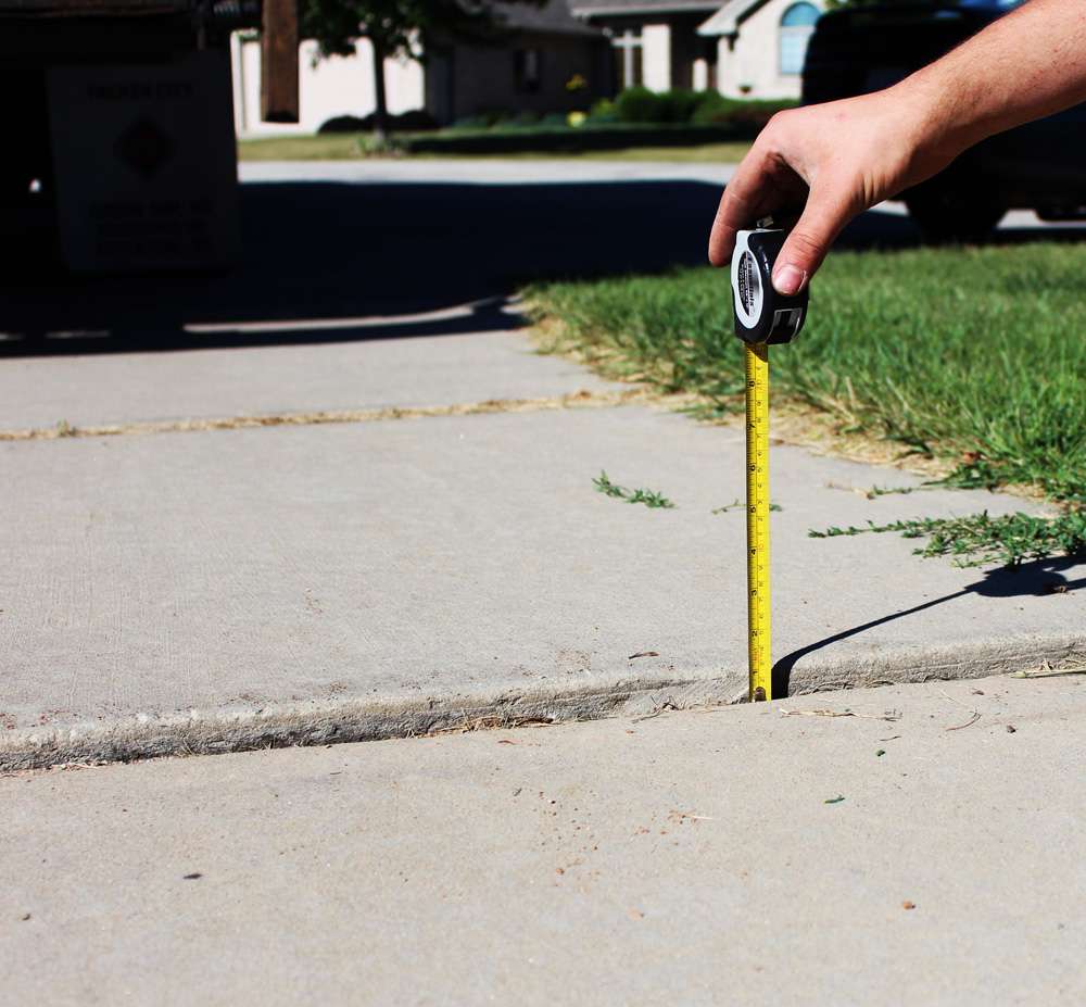 a person is measuring a sidewalk with a tape measure