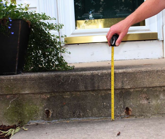 a person measuring a concrete step with a tape measure