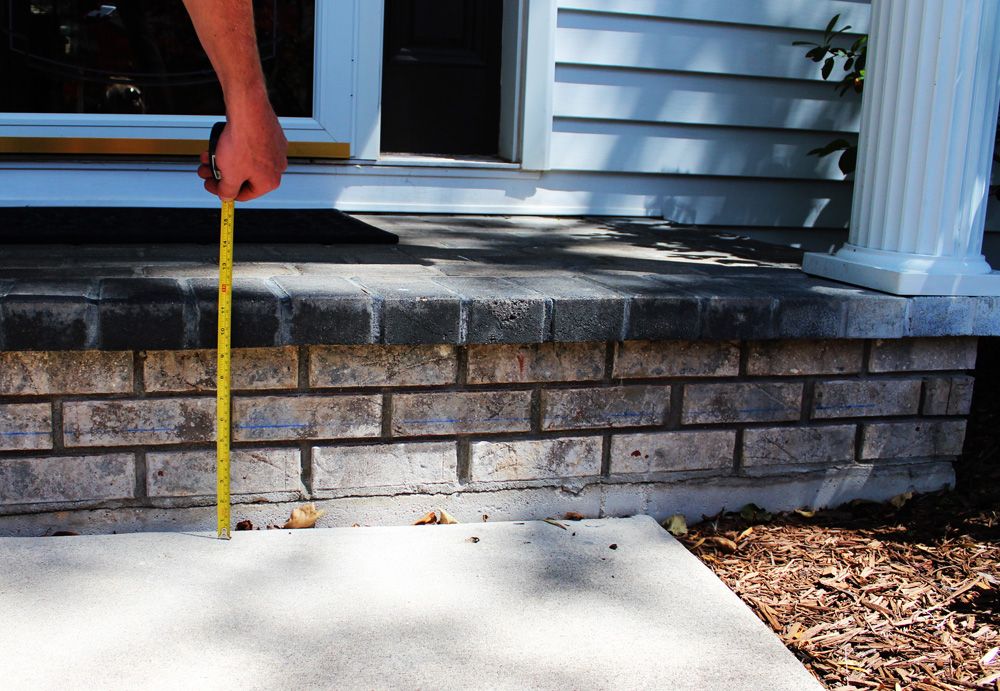 a person measuring a porch with a tape measure