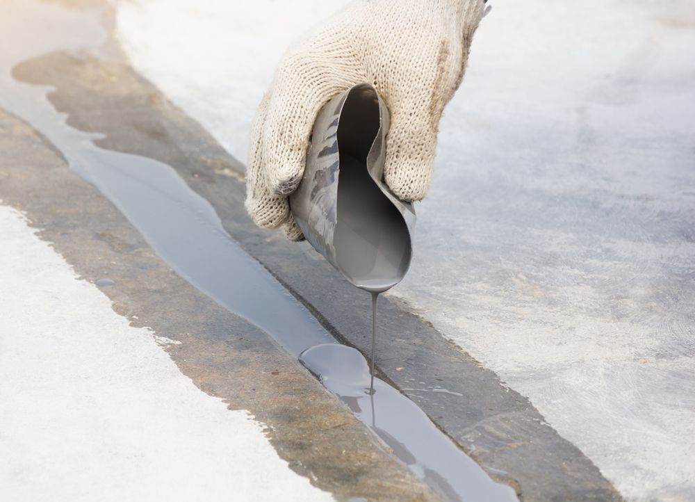 A person is pouring epoxy into a hole in the ground.