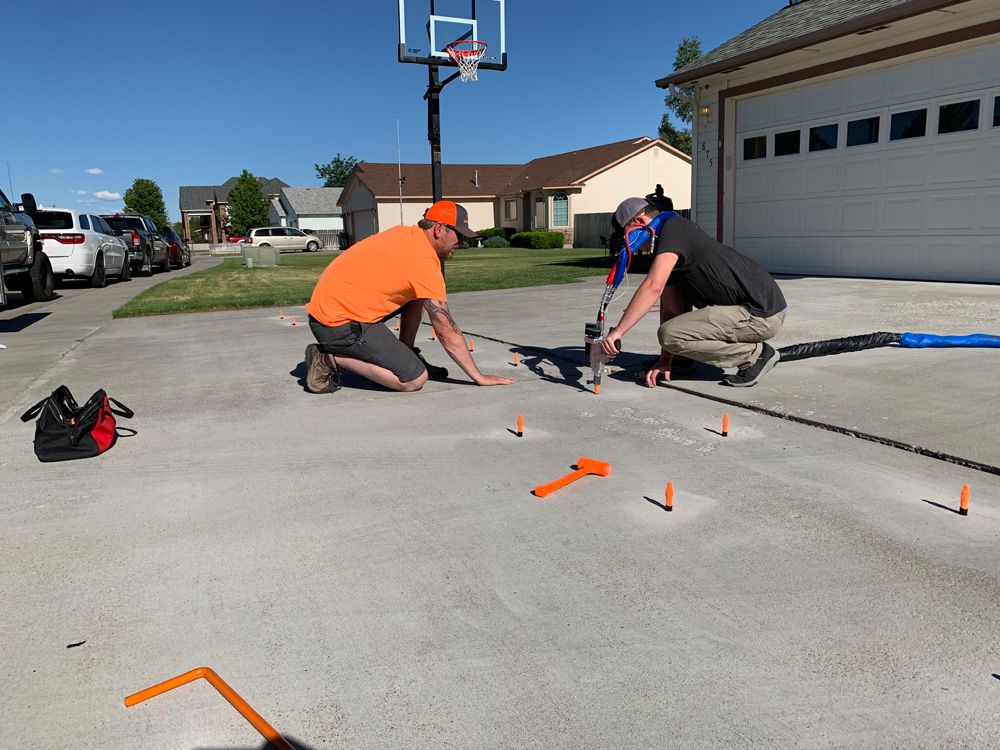 two men are working on a basketball hoop in a driveway