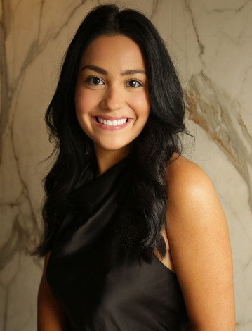 Smiling person in a black sleeveless top standing before a marble wall background