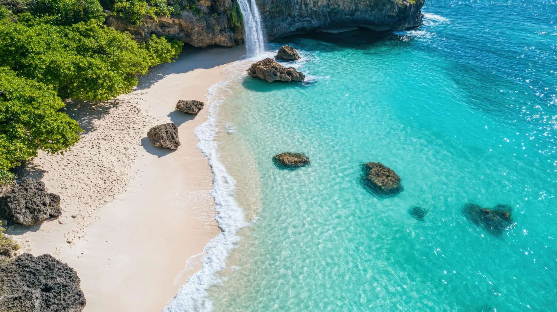An aerial view of a beach with a waterfall in the background.