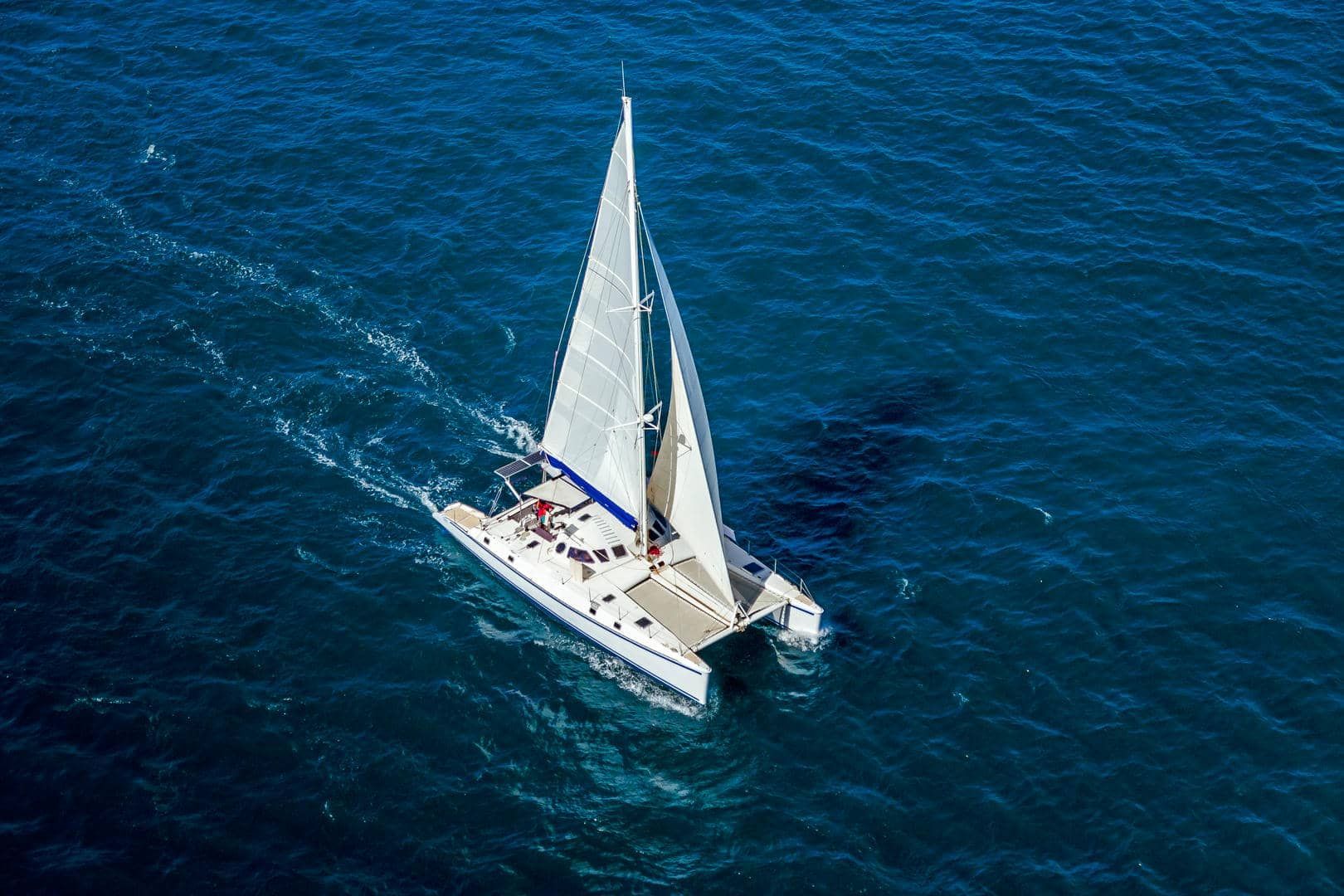 An aerial view of a sailboat in the ocean.