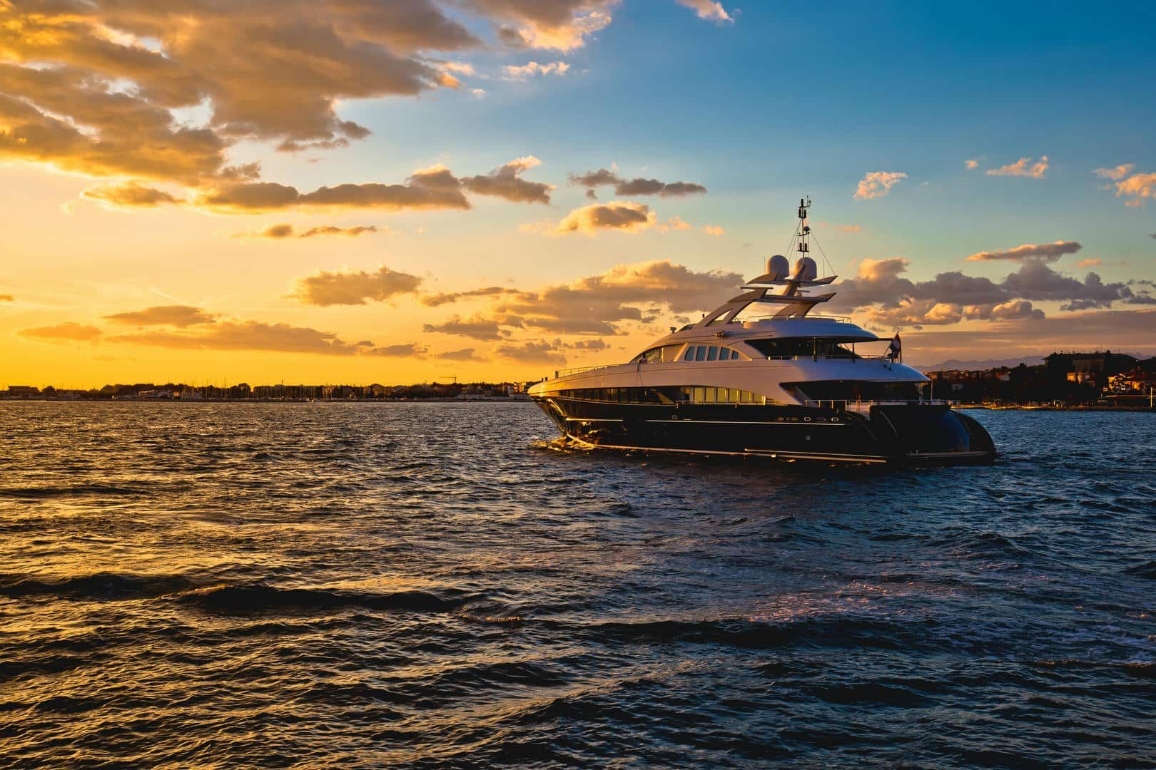 A large yacht is floating on top of a body of water at sunset.