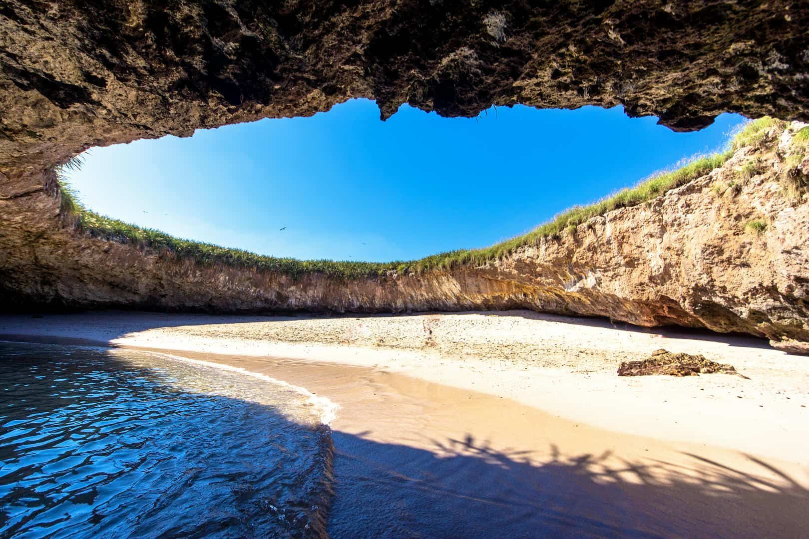 A view of a beach from inside a cave.
