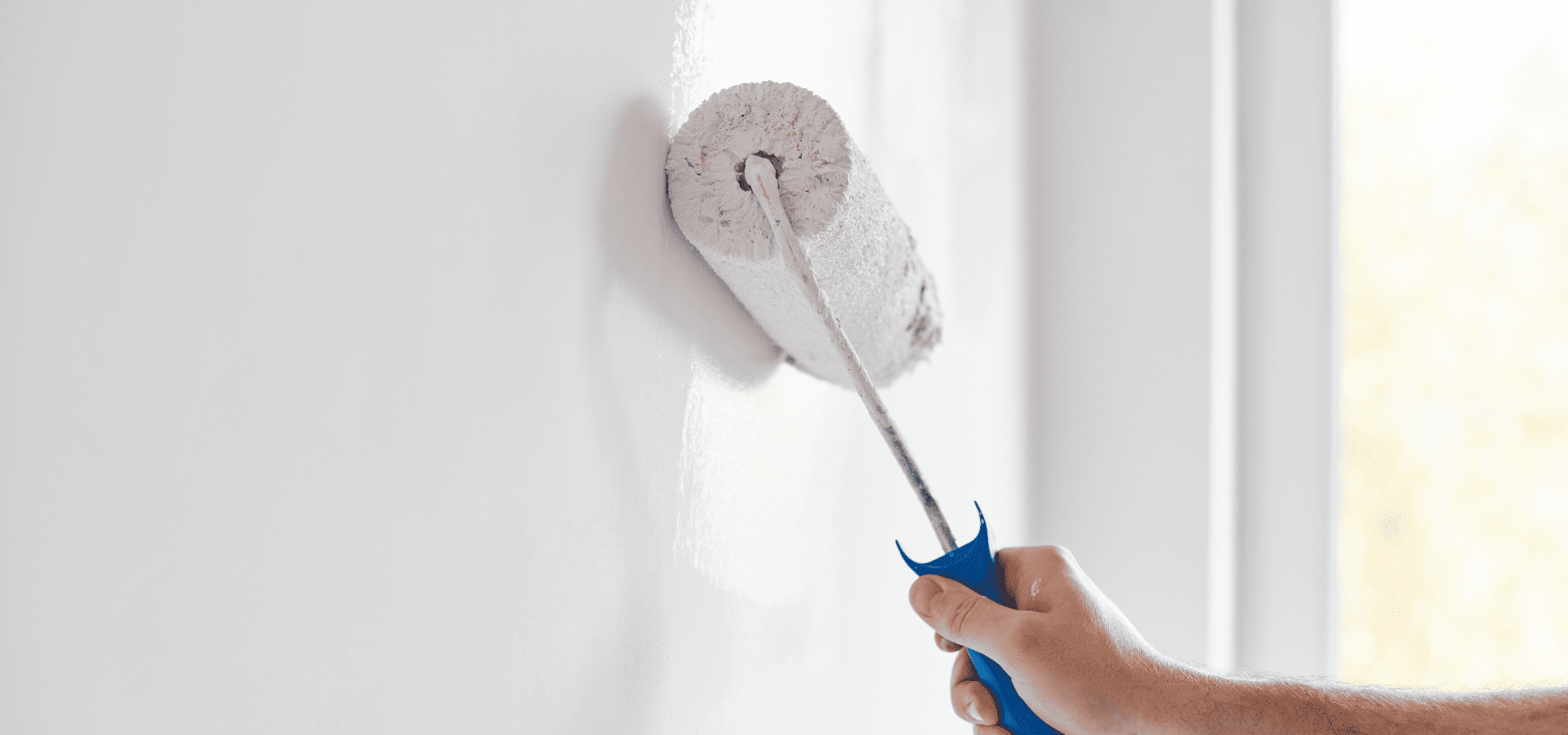 House painter applying white paint onto walls with a roller