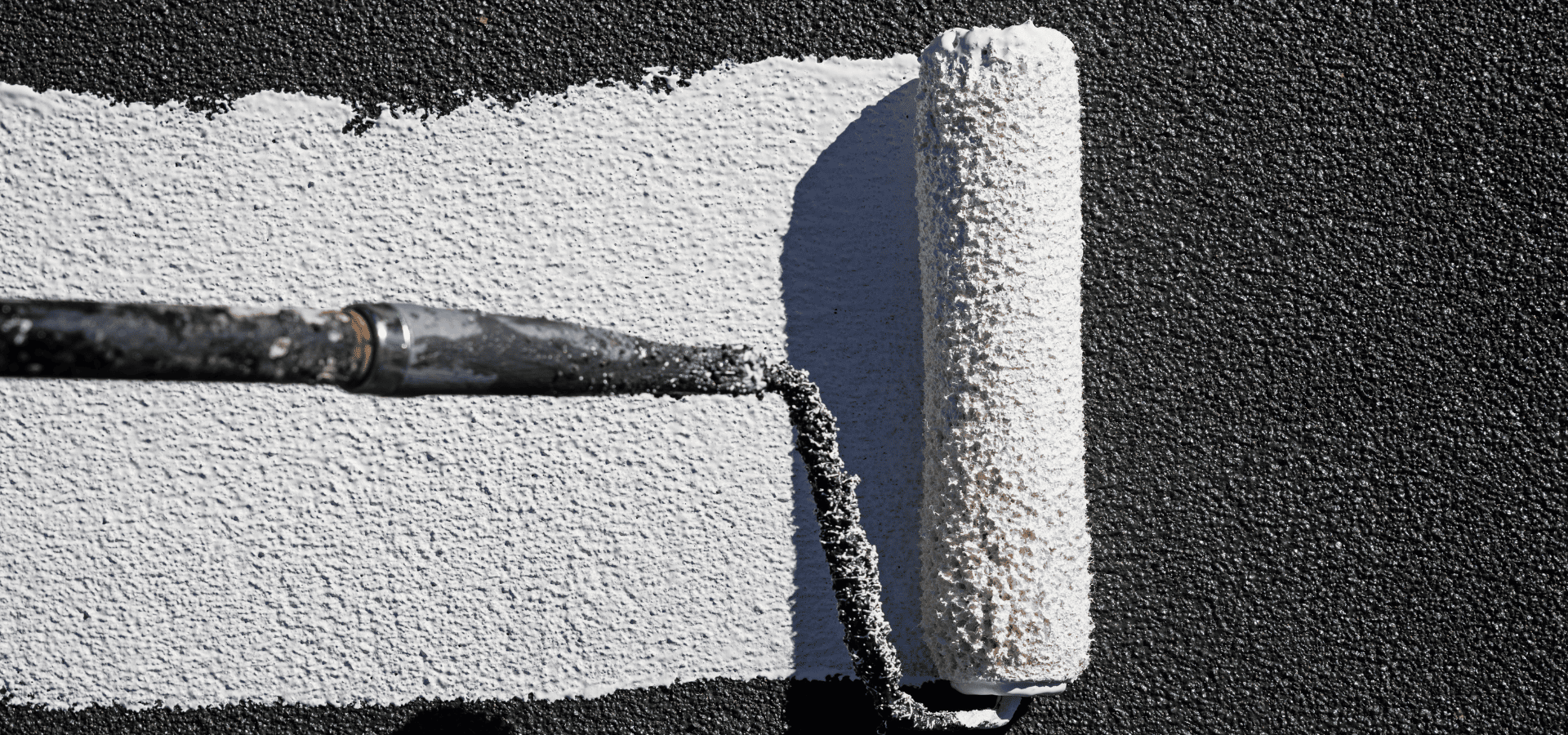 Rolling white reflective paint over a black roof