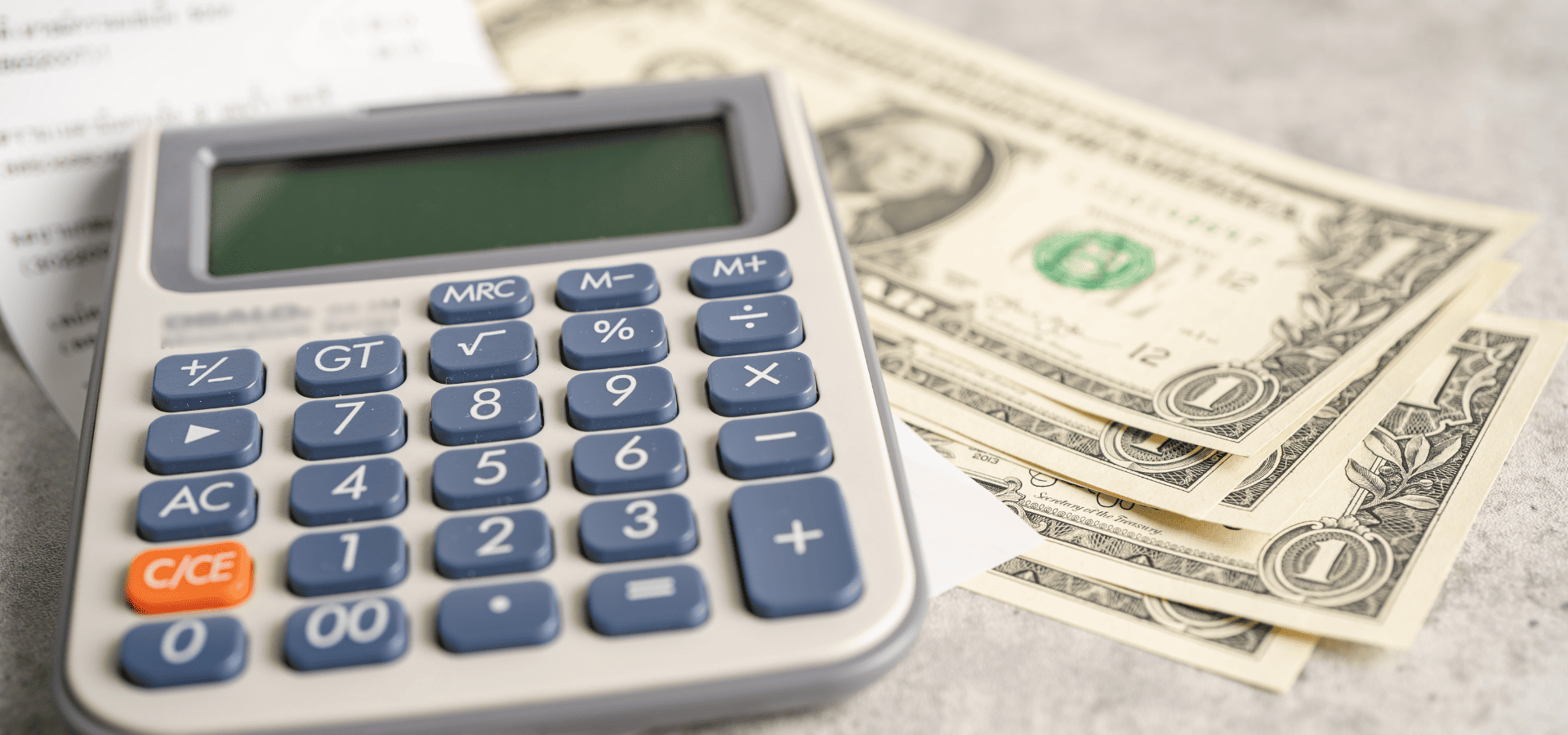 A calculator used to calculate the cost of house painting with lower-VOC paints, with some dollar bills underneath