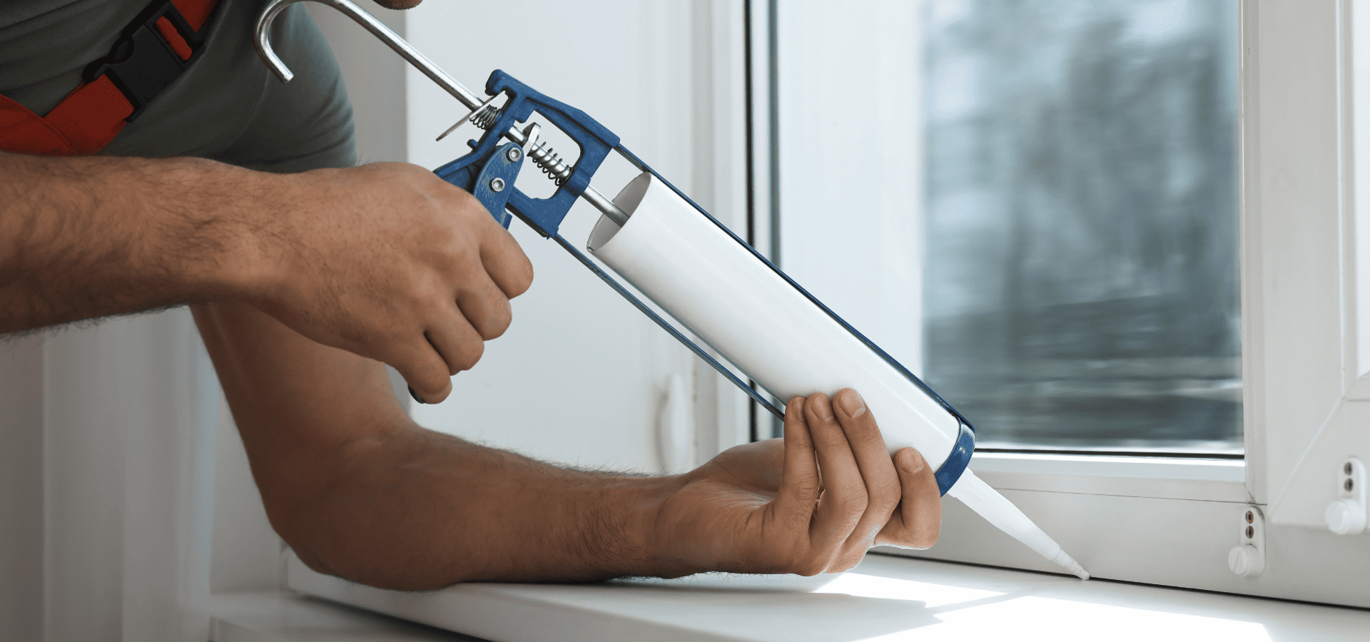 Employee from Renewed Walls Painting sealing windows with a caulking gun