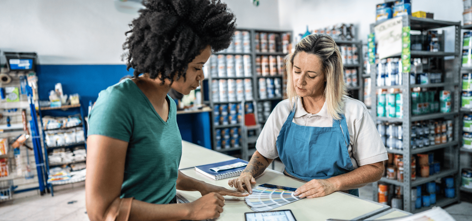 Homeowner speaking to paint store staff about choosing and buying house paint