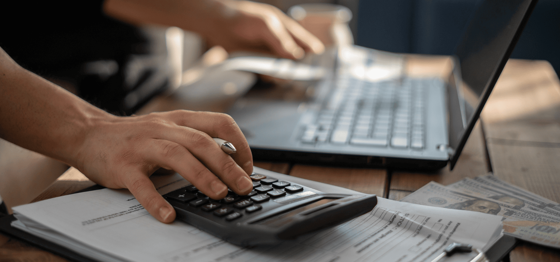 A homeowner using a calculator and laptop to plan his house painting budget