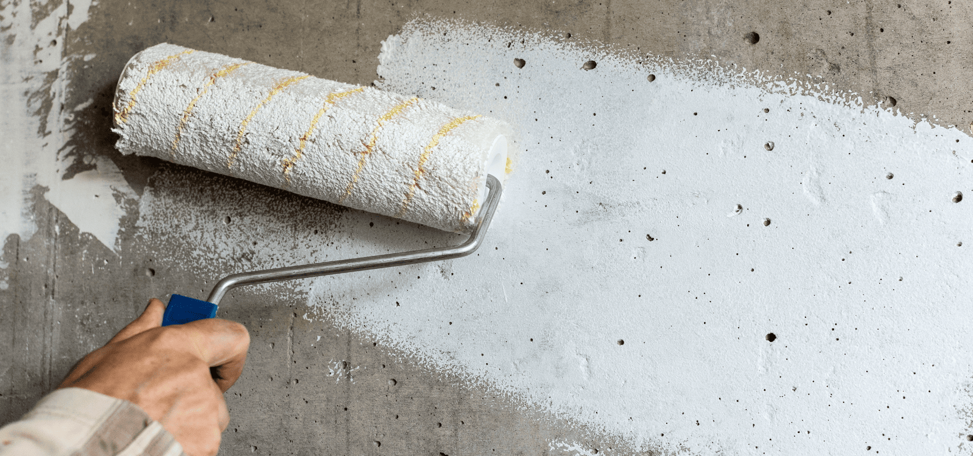 Painting a concrete wall white using a hand roller