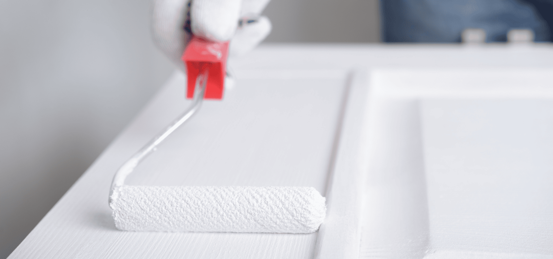 Employee painting a wooden door white with a mini roller