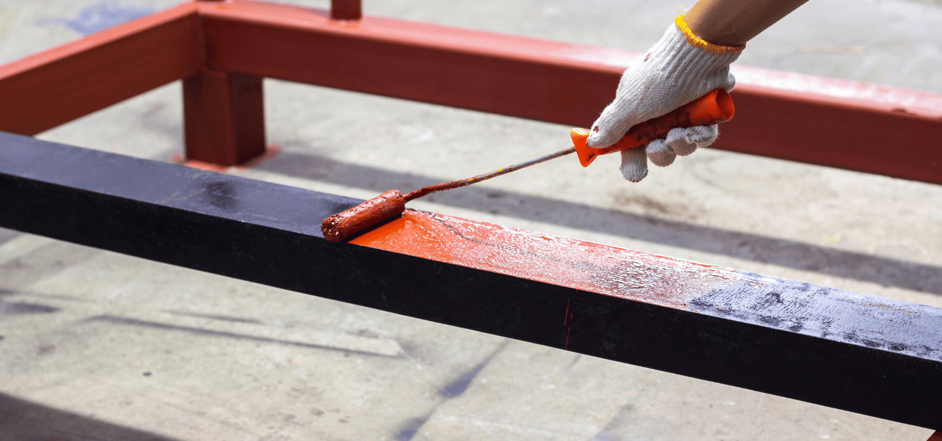 Worker from Renewed Walls Painting painting a metal beam with red rust-inhibiting paint