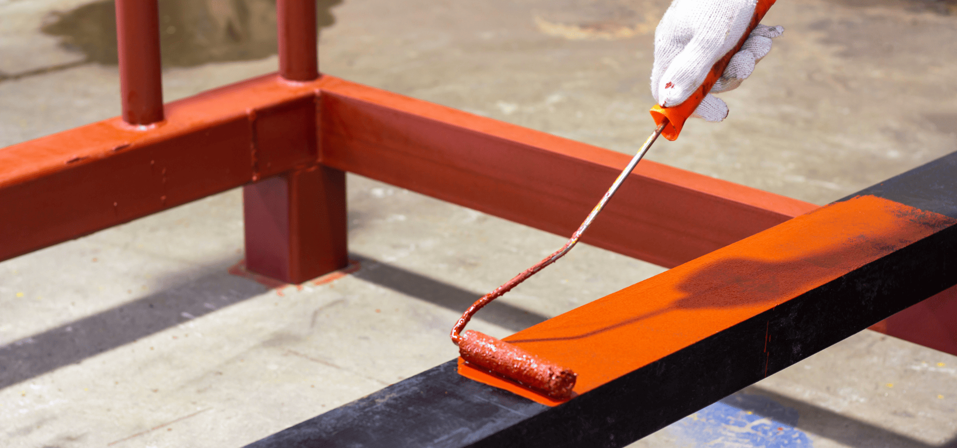 Painting metal pipes red with a mini roller