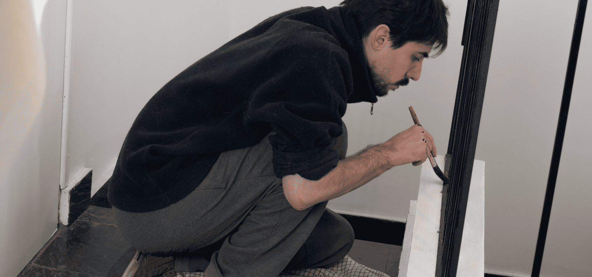 Homeowner painting his stair spindles black with a paintbrush