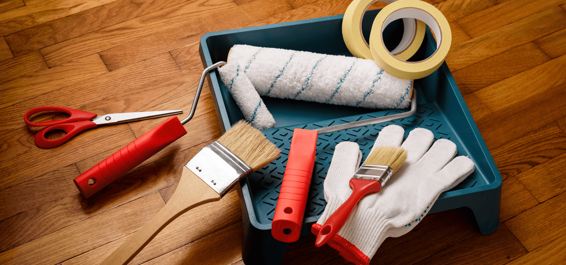 Painting gloves, brush, roller, and tape on a paint tray