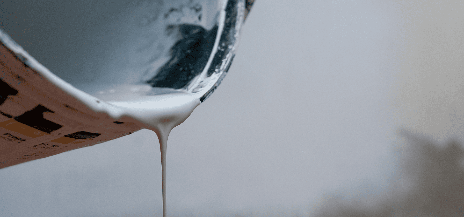 Pouring white oil-based paint from a paint can into a paint tray