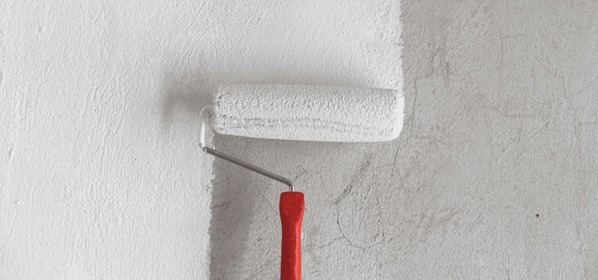 Rolling white paint onto a slightly cracked concrete wall