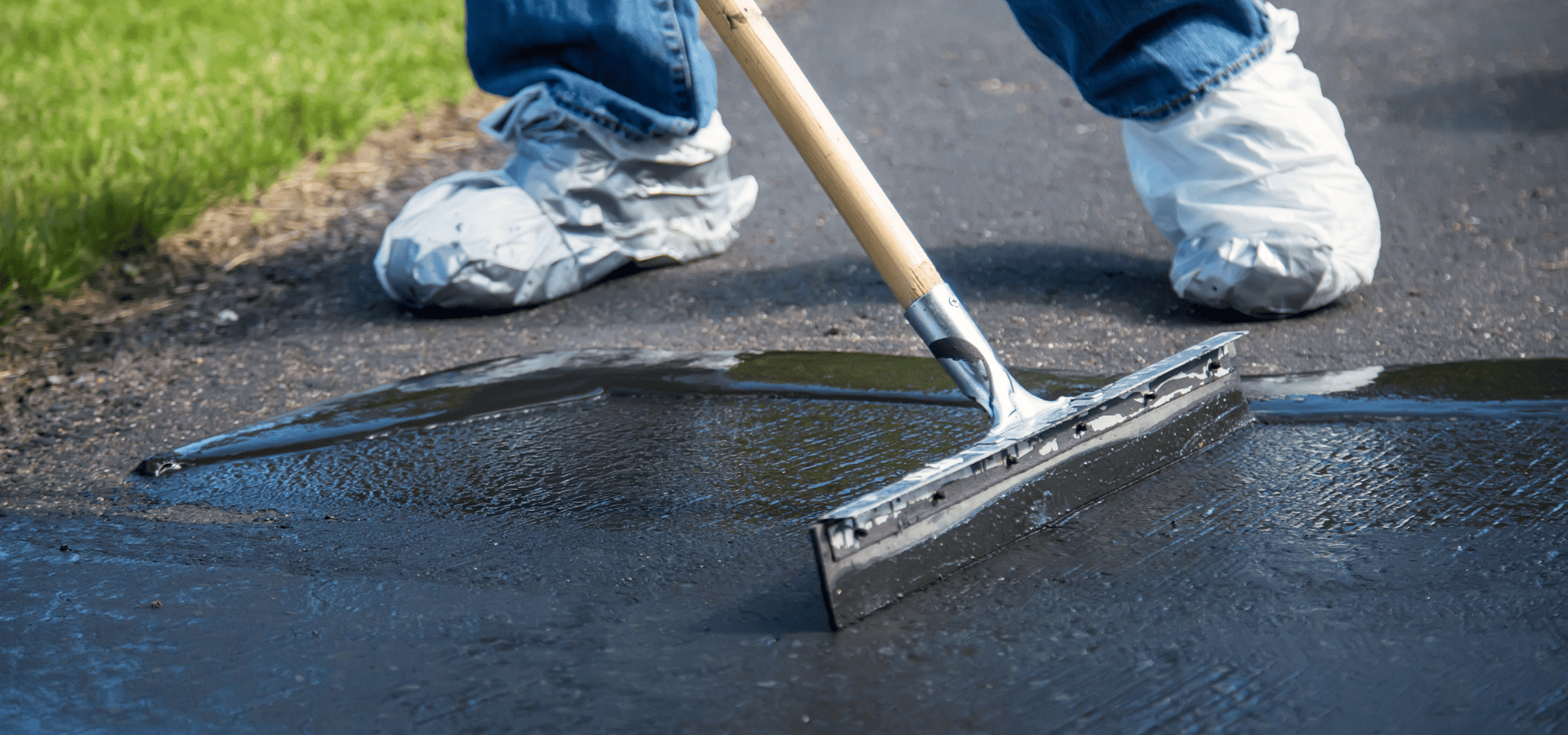 Squeegeeing asphalt sealer after pouring it onto the asphalt driveway