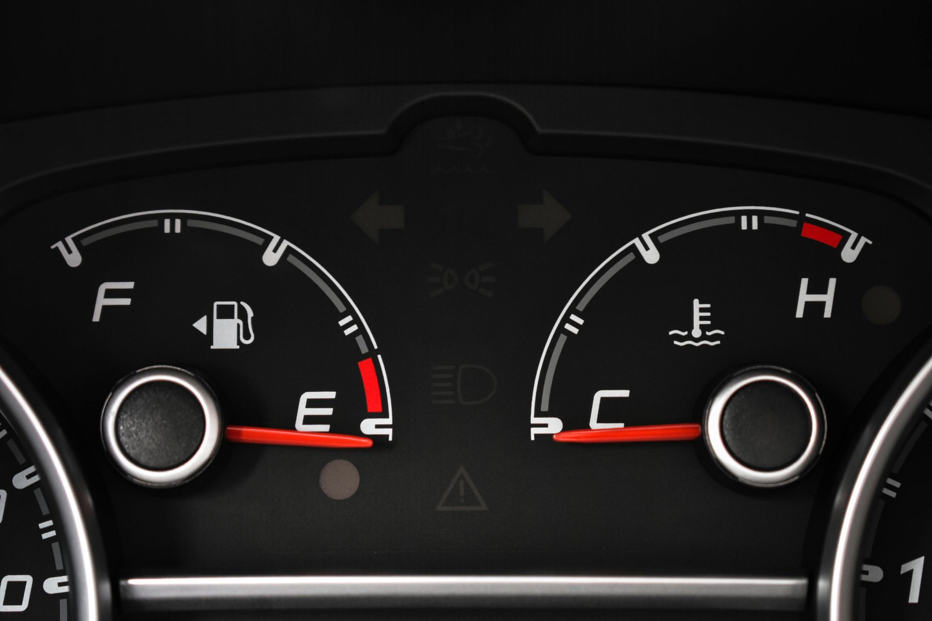 Car dashboard showing fuel gauge near empty, and engine temperature gauge at normal operating temperature.