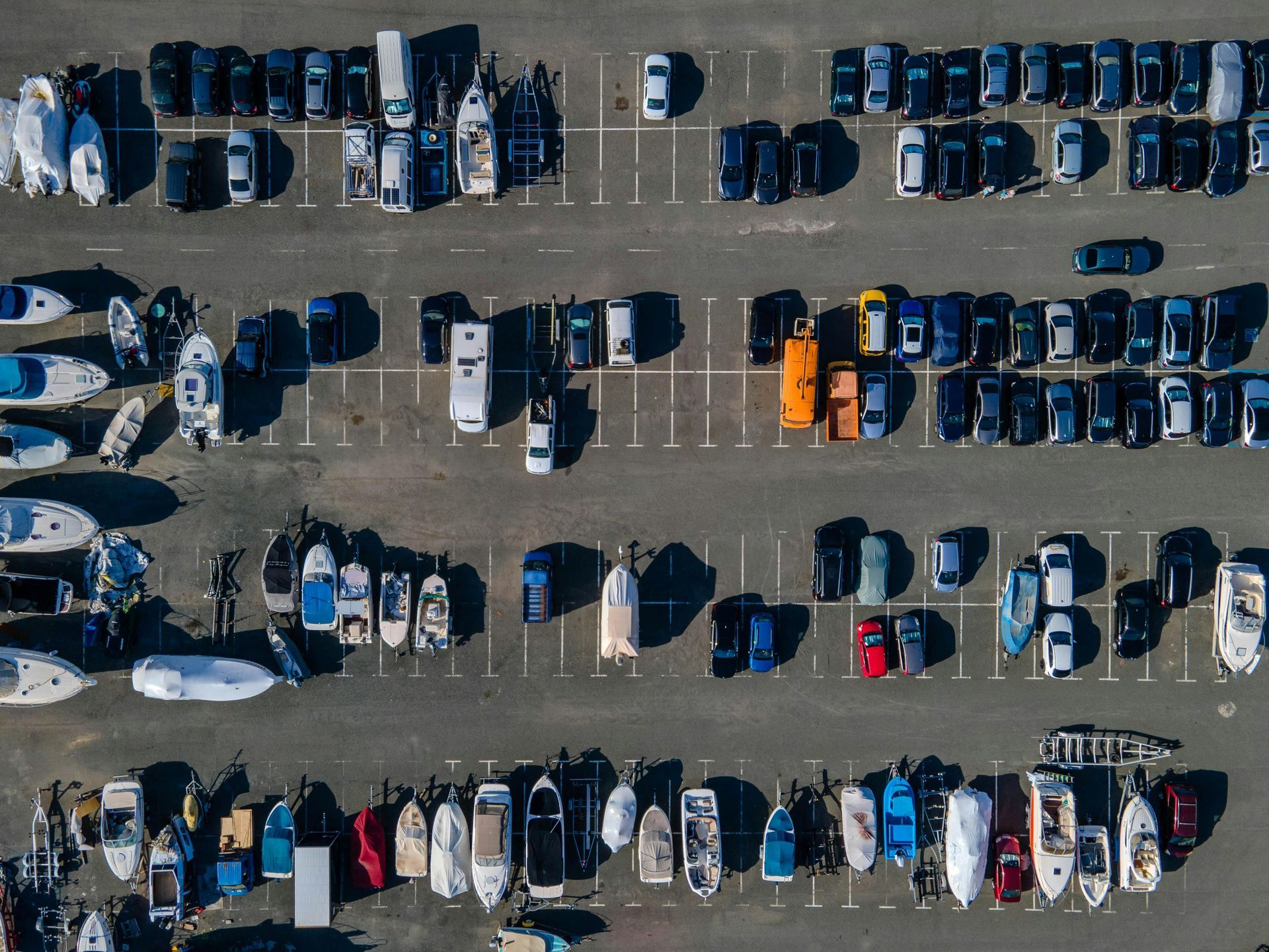 Overhead view of boats and vehicles parked in a large outdoor lot.