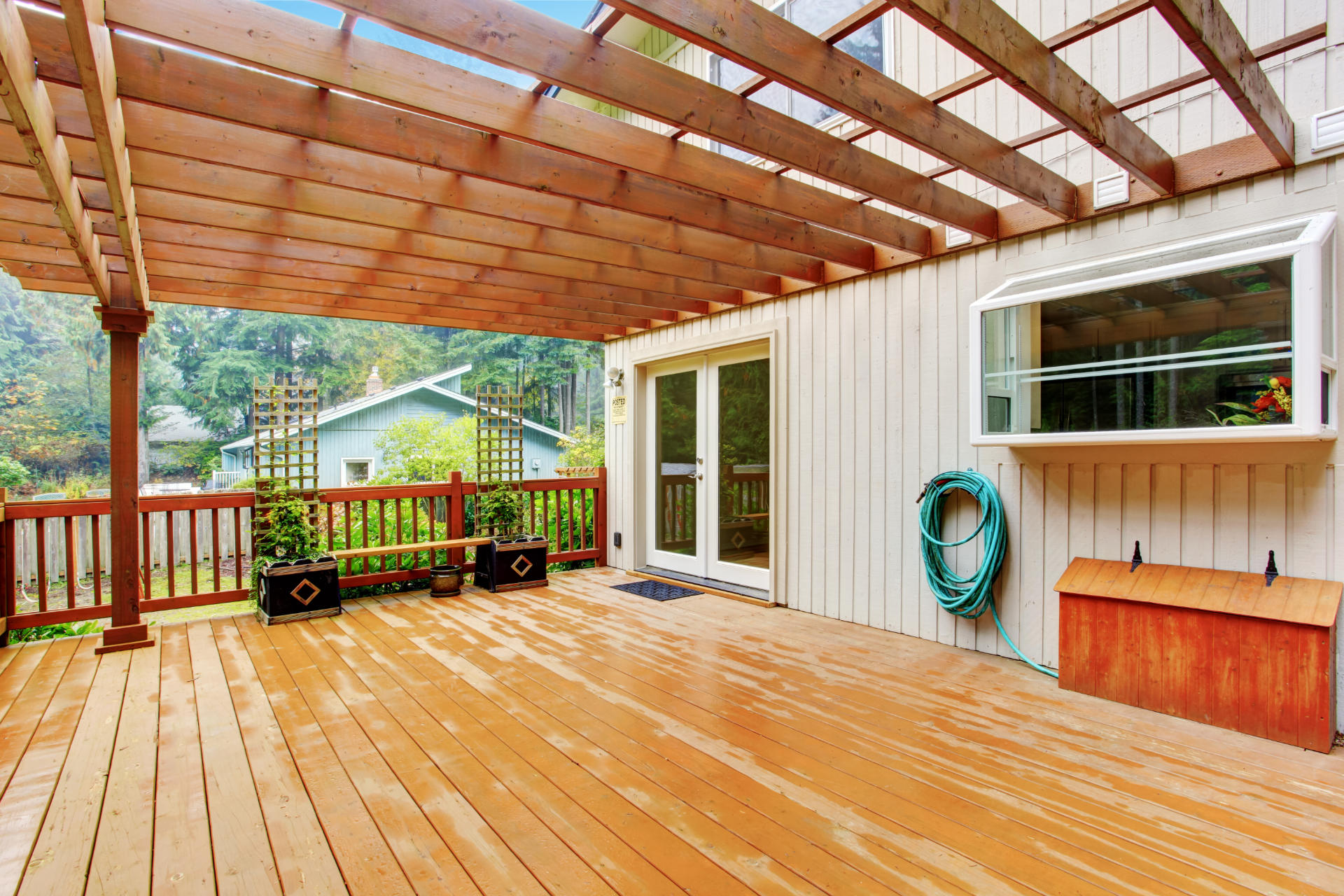 A nice photo of a large deck that has a pergola built into the deck. The pergola offers semi-shade to part of the deck.