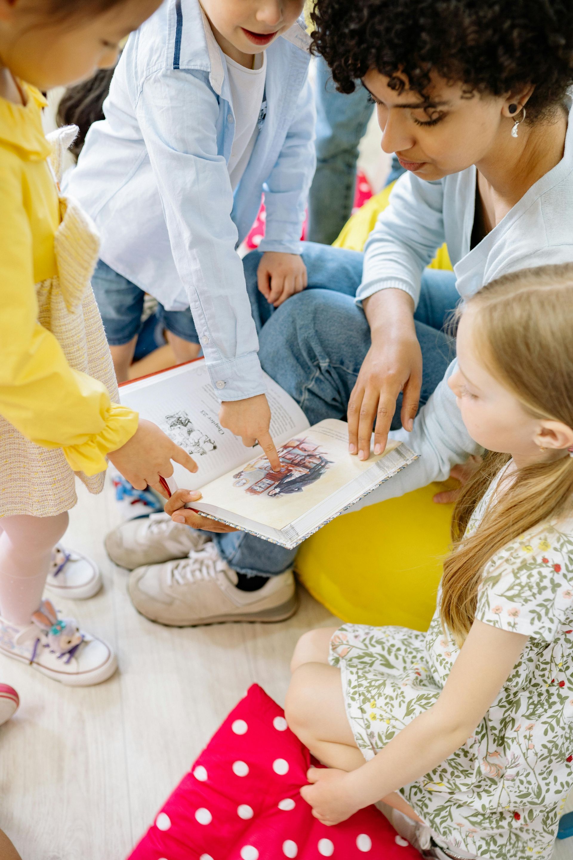 A woman is reading a book to a group of children.