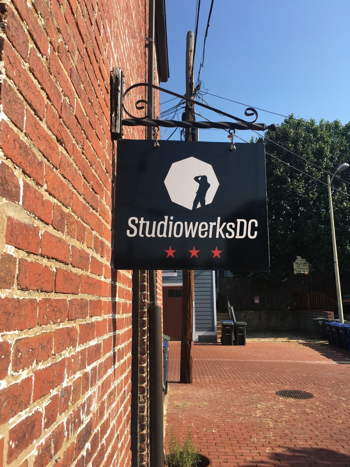 Studio Werks DC sign on brick building; black with white logo, red stars.