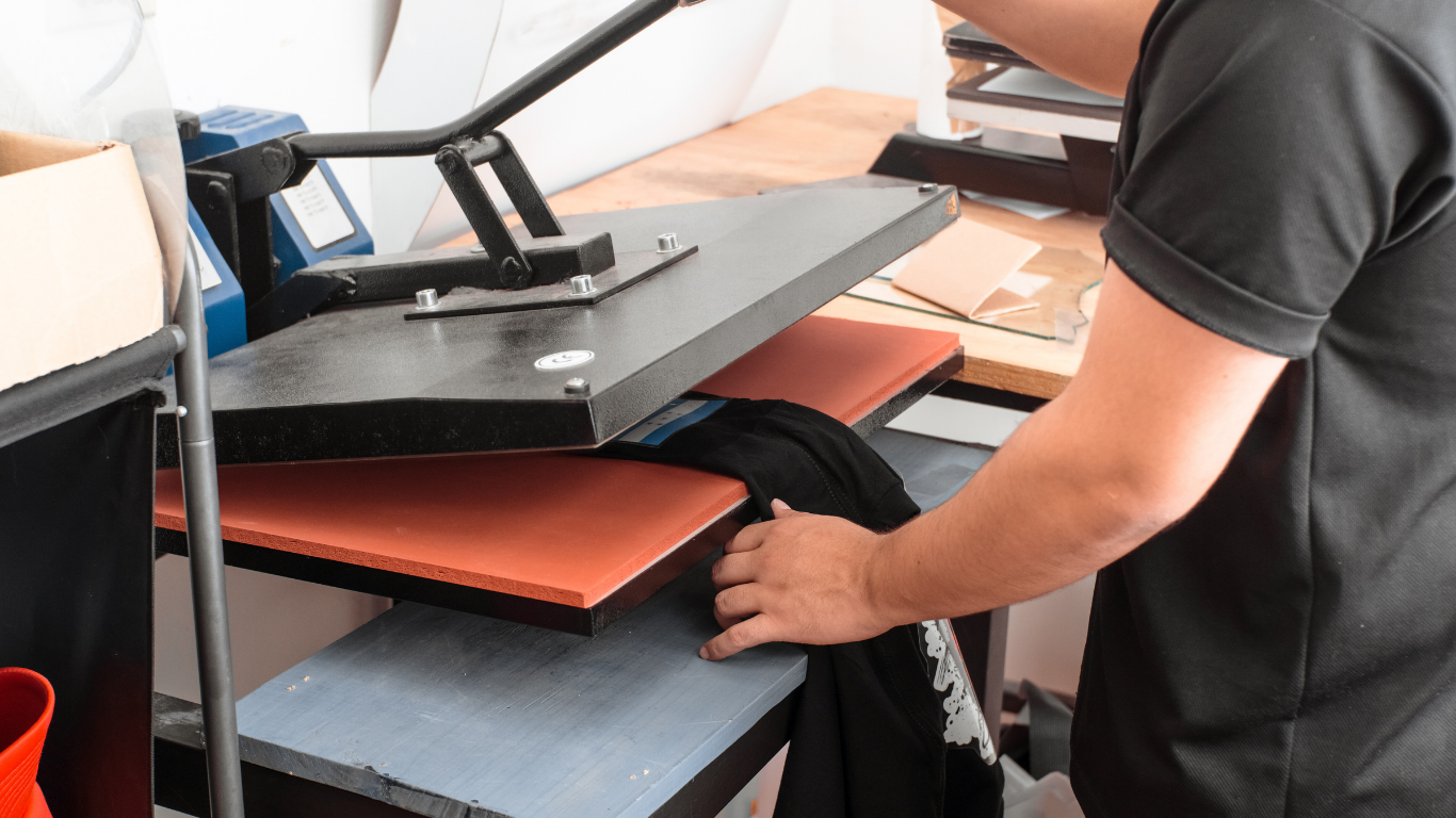 Person using a heat press to apply a design on a black t-shirt.