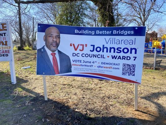 Political sign for 'VJ' Johnson, DC Council Ward 7. Blue and white with candidate photo, “Building Better Bridges.”