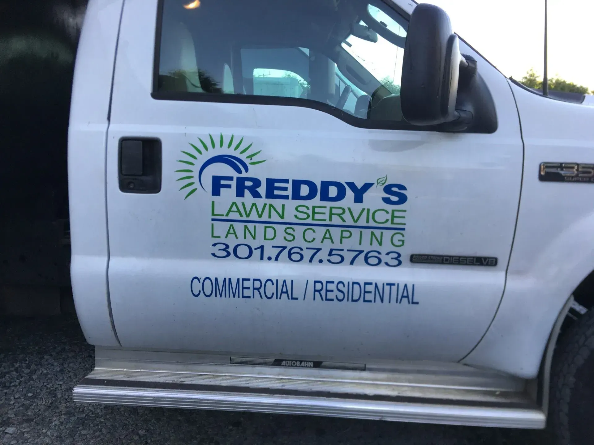 White truck door with Freddy's Lawn Service logo and phone number.