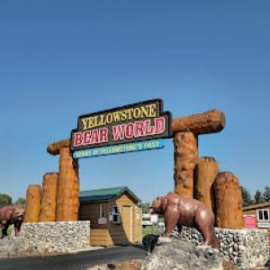 A sign for yellowstone bear world with a statue of a bear in front of it.