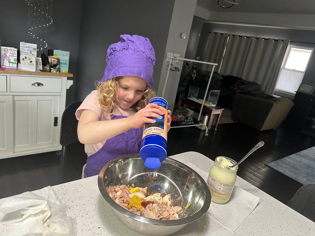 child in purple chef hat mixing ingredients in a large bowl