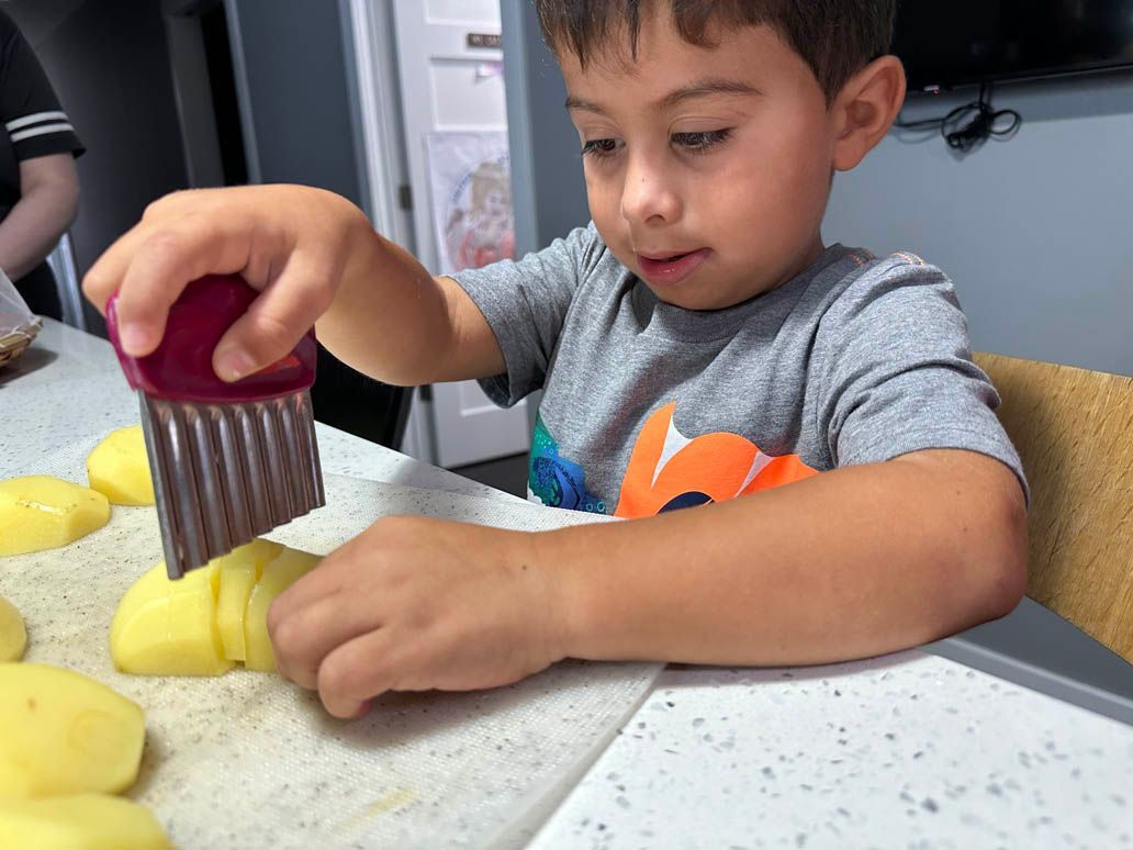 a child slicing a peeled potato with a hand held slicer