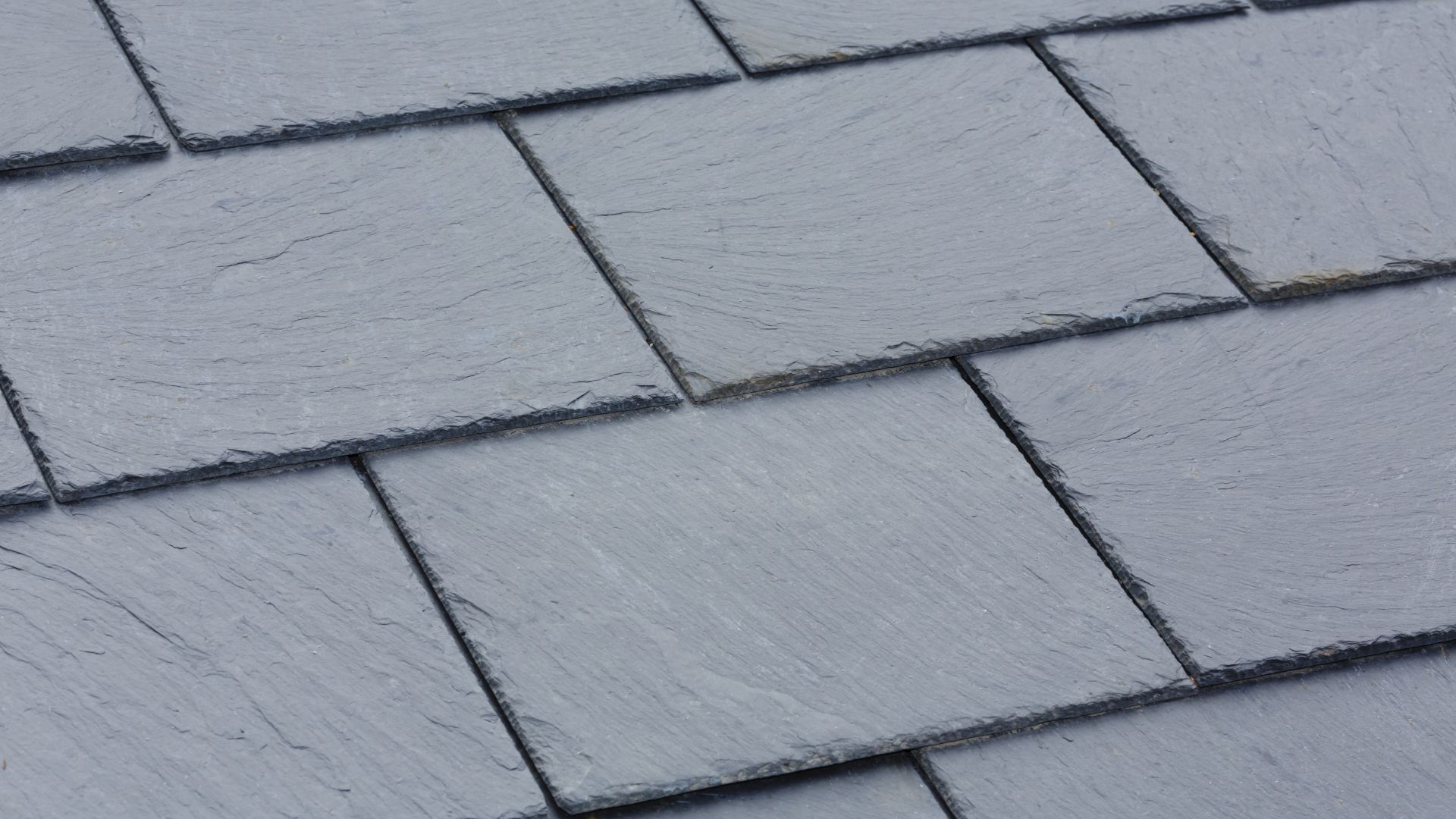 Close-up view of overlapping gray slate roof tiles.