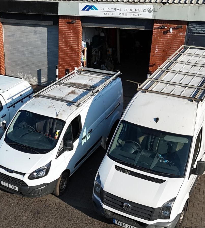 White vans with roof racks parked outside a brick building with 