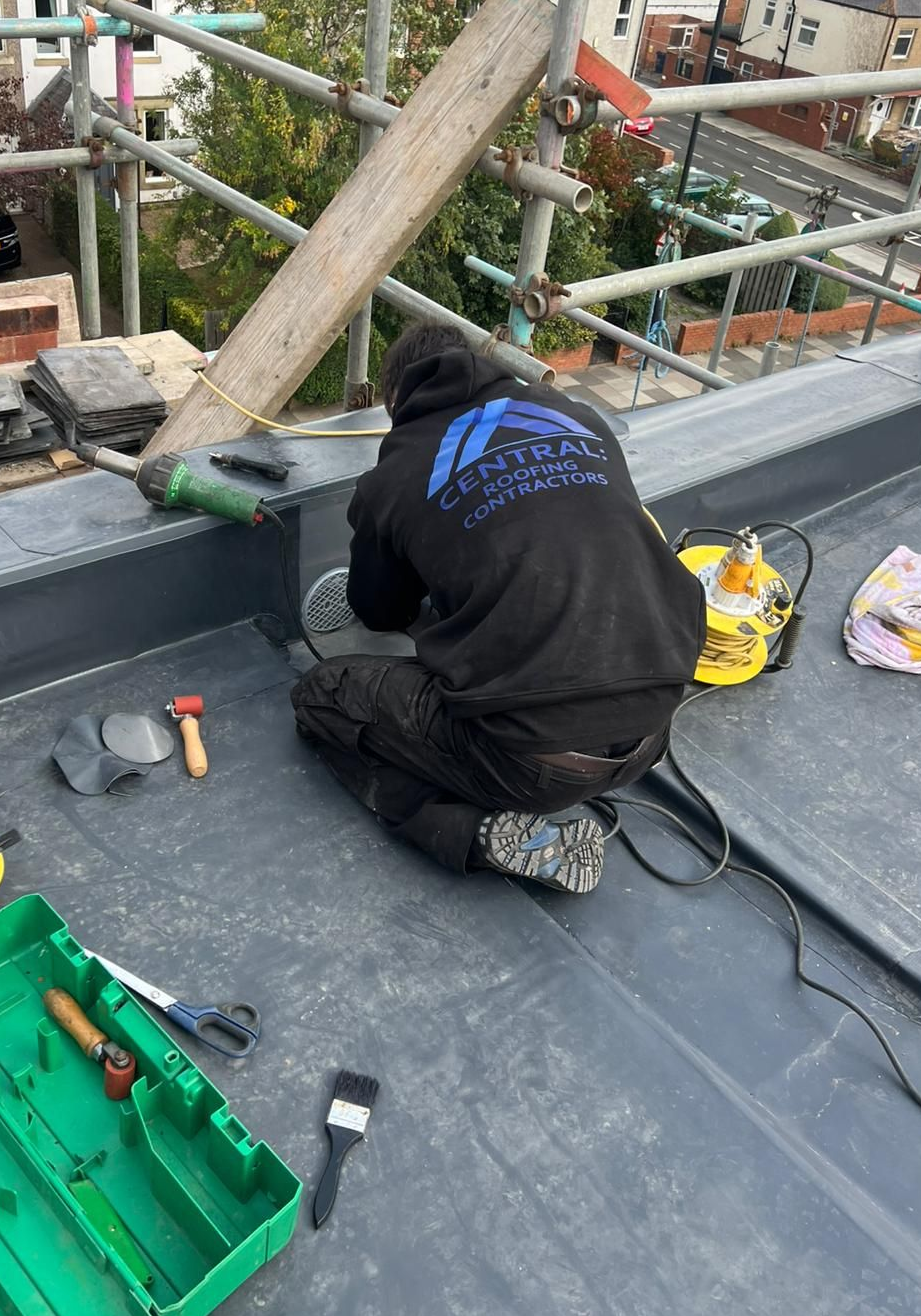 Flat gray roof with a skylight, against a backdrop of brick buildings.