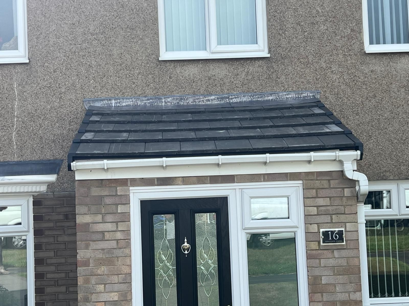 Brick entryway with black door under a small tiled roof; house number 13.